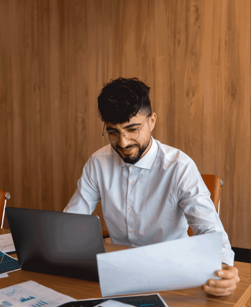 Person reviewing documents on a laptop, with text about BoQ library, client estimate management, and invoices